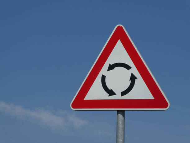 Circular Intersection - warning traffic road sign roundabout against blue sky